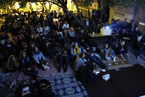 Projection de cinéma en plein air avec Écran Voisin aux Grands Voisins à Paris, public installé dans la cour en soirée