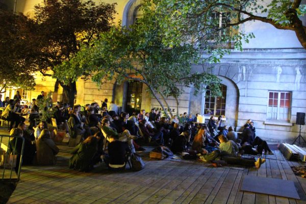Séance de cinéma en plein air Écran Voisin dans la cour des Grands Voisins à Paris, ambiance nocturne et public rassemblé