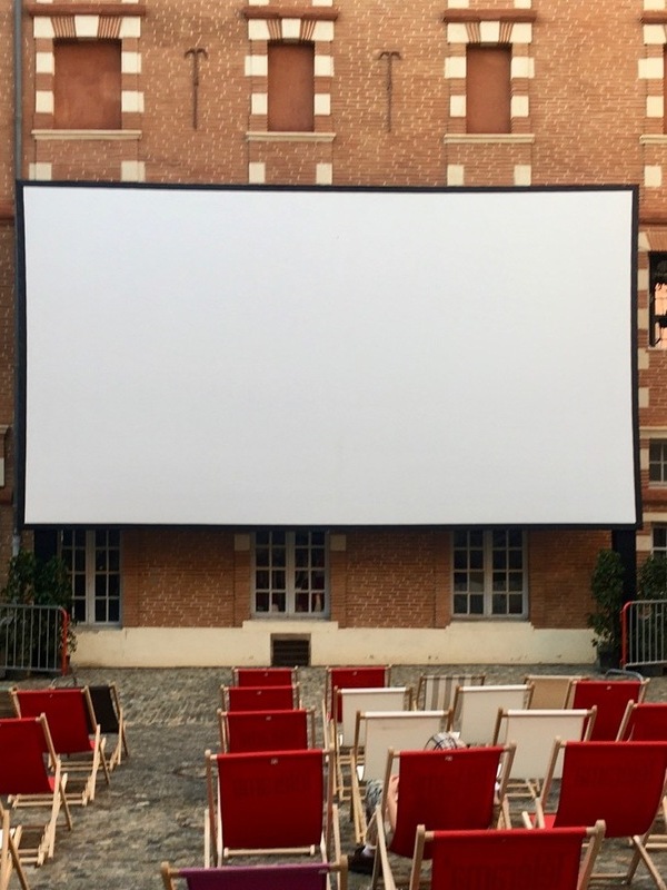 Projection de cinéma en plein air avec écran et chaises, programmation de films en extérieur